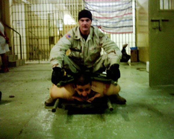 Trung sĩ Ivan "Chip" Frederick, quân nhân cấp cao nhất tại nhà tù Abu Ghraib vào mùa thu năm 2003, đang ngồi trên một tù nhân. Ông ta đã bị kết án tám năm tù. Ảnh: Wikipedia